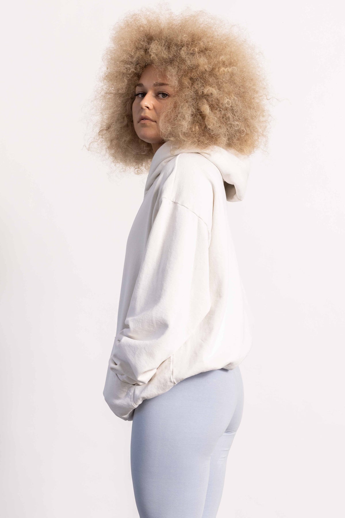 White female model with edgy style and big afro hair style wearing a heavyweight cotton off white hoodie