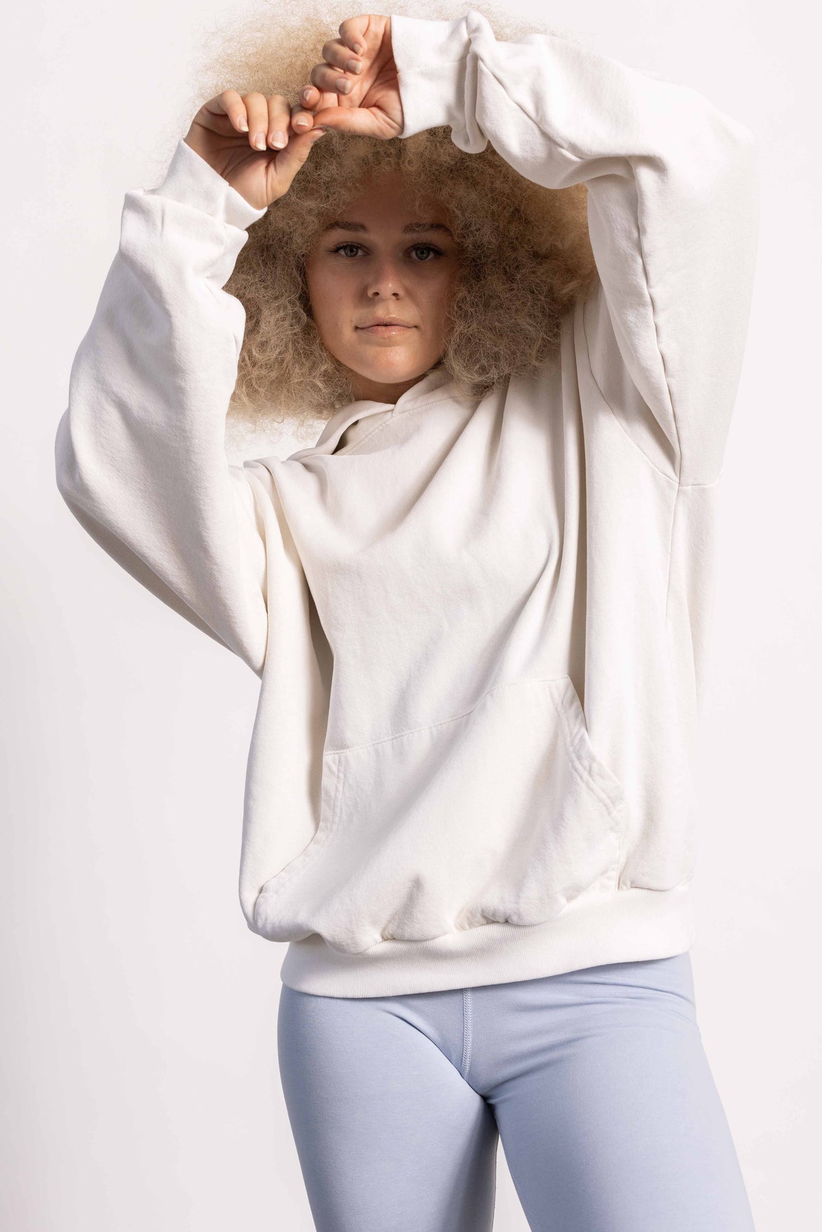 White female model with edgy style and big afro hair style wearing a heavyweight cotton off white hoodie