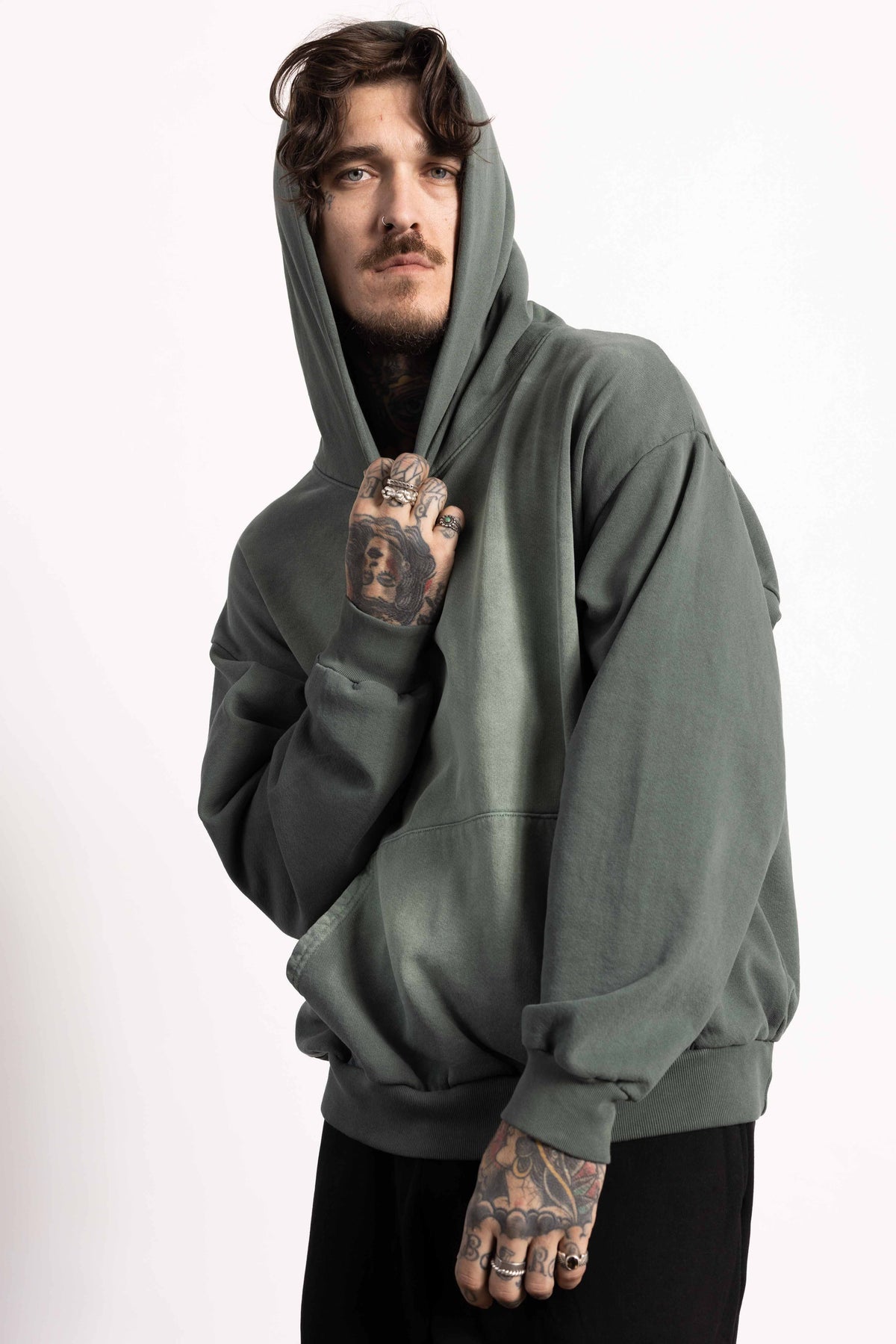 White male model with edgy style wearing a heavyweight cotton vintage green hoodie