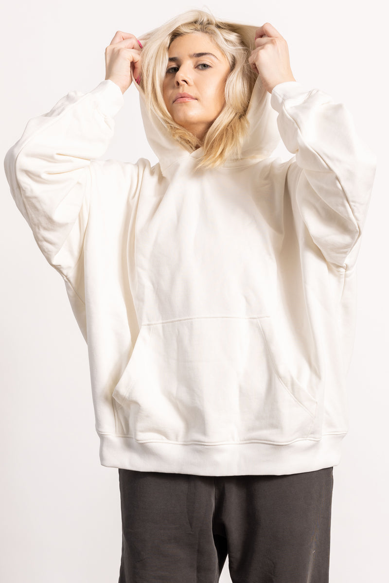 White blonde female model with edgy style wearing a off white drop shoulder pima cotton hoodie