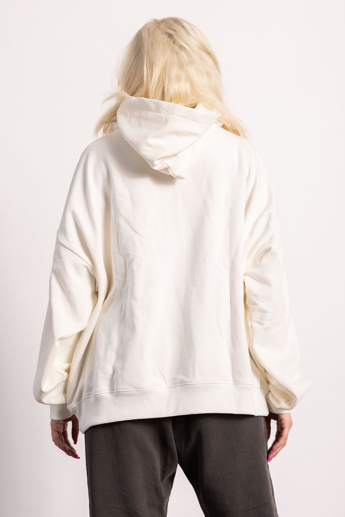 White blonde female model with edgy style wearing a off white drop shoulder pima cotton hoodie